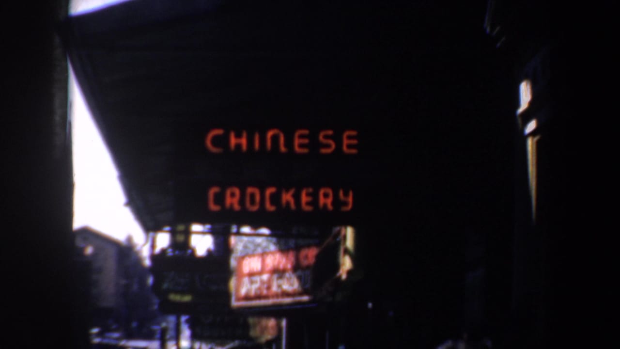 Dark nighttime storefront with red Chinese Crockery neon sign and street shadows.