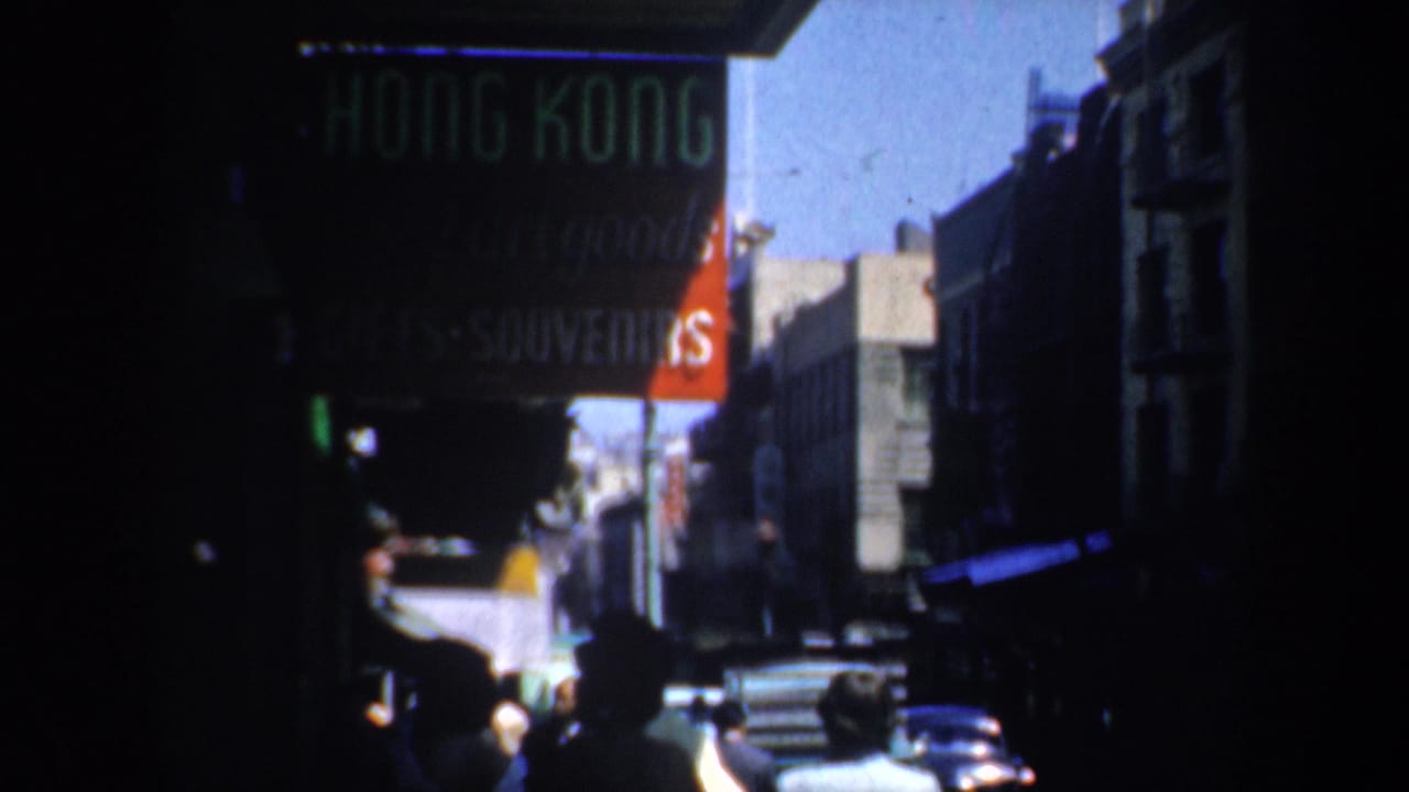 A shadowed sidewalk scene shows pedestrians, cars, awnings, and a Hong Kong souvenir sign.