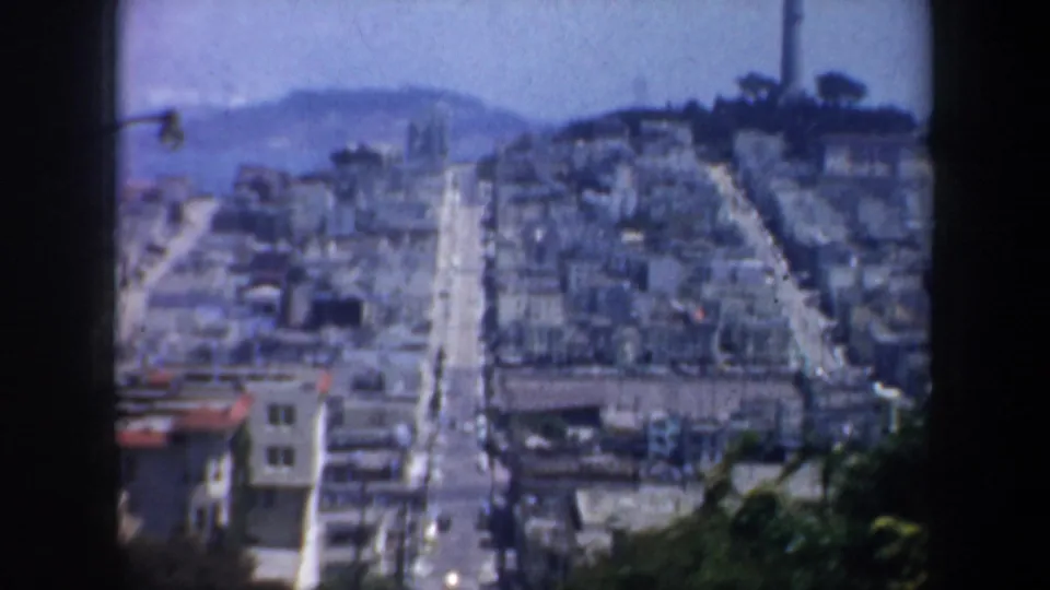San Francisco hillside blocks in 1957, with a long straight street descending through dense buildings toward the bay.