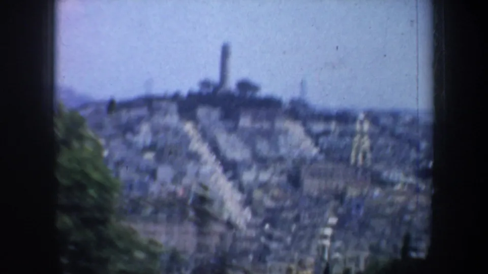 Blurred 1957 8mm view over San Francisco hillside buildings, with a skyline tower likely to be Coit Tower.