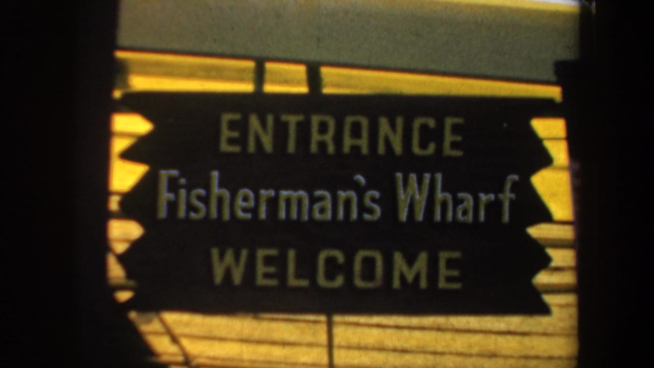 Fisherman's Wharf entrance sign on a sunlit wooden background.