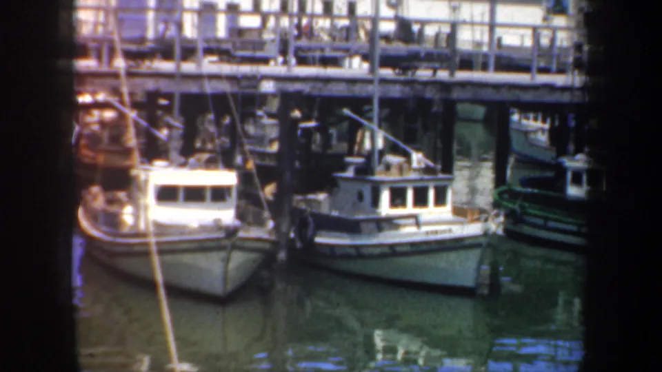 San Francisco waterfront frame with small moored boats, dock pilings, pier railings, and soft 8mm color fading.