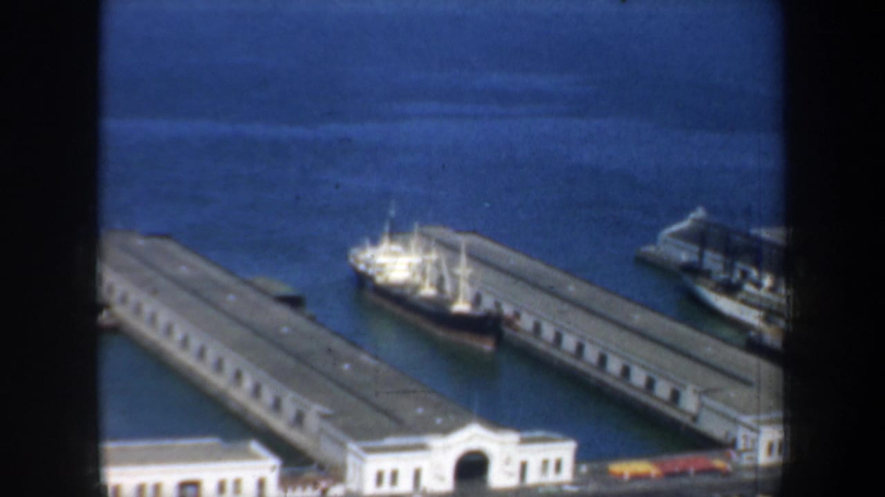 1957 San Francisco harbor view showing long pier buildings and a vessel moored alongside the waterfront.