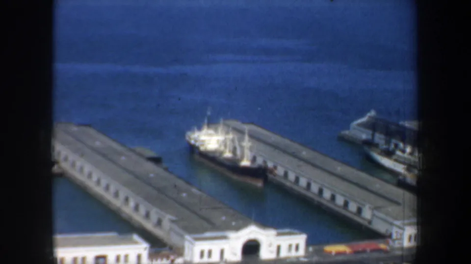 1957 San Francisco harbor view showing long pier buildings and a vessel moored alongside the waterfront.