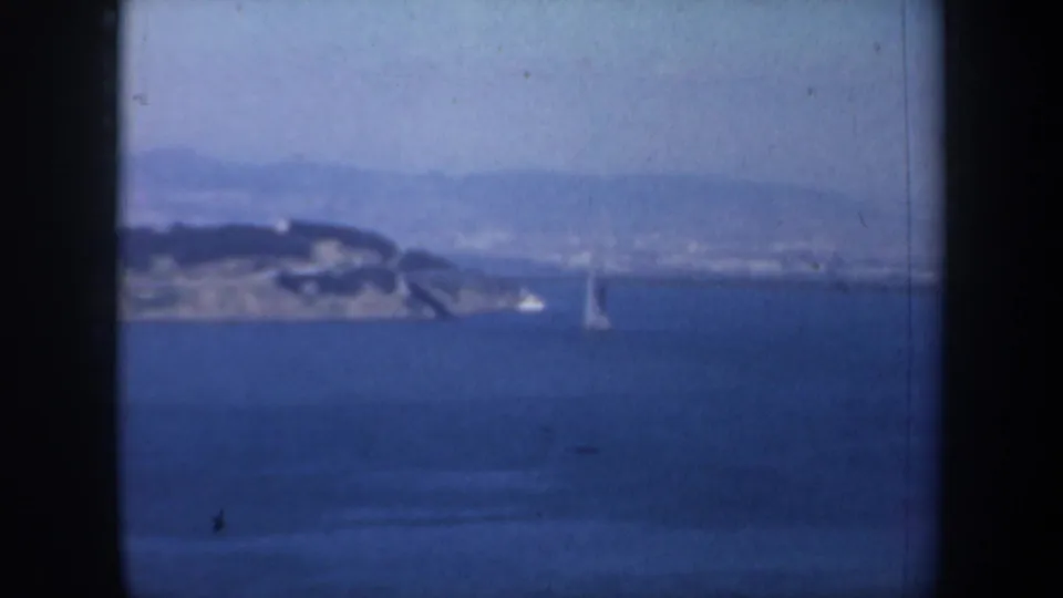 Distant 1957 San Francisco Bay view with Alcatraz Island visible at left and a sailboat crossing the water.
