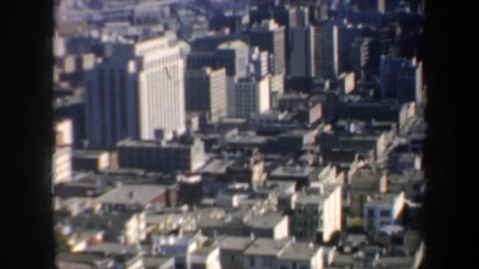 Elevated 1957 San Francisco view showing downtown buildings, rooftops, and a glimpse of waterfront structures.