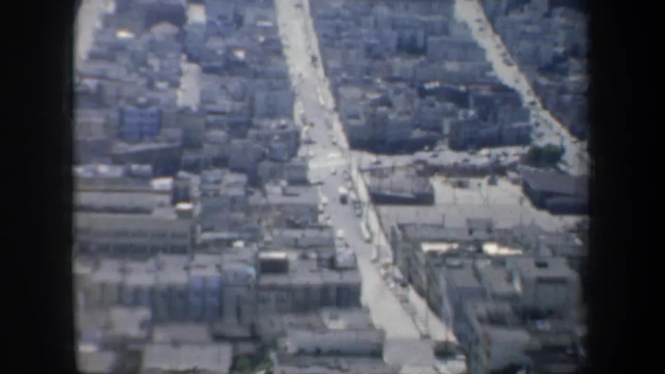 1957 San Francisco street grid and dense urban blocks seen from above, with a dark window frame at the side.