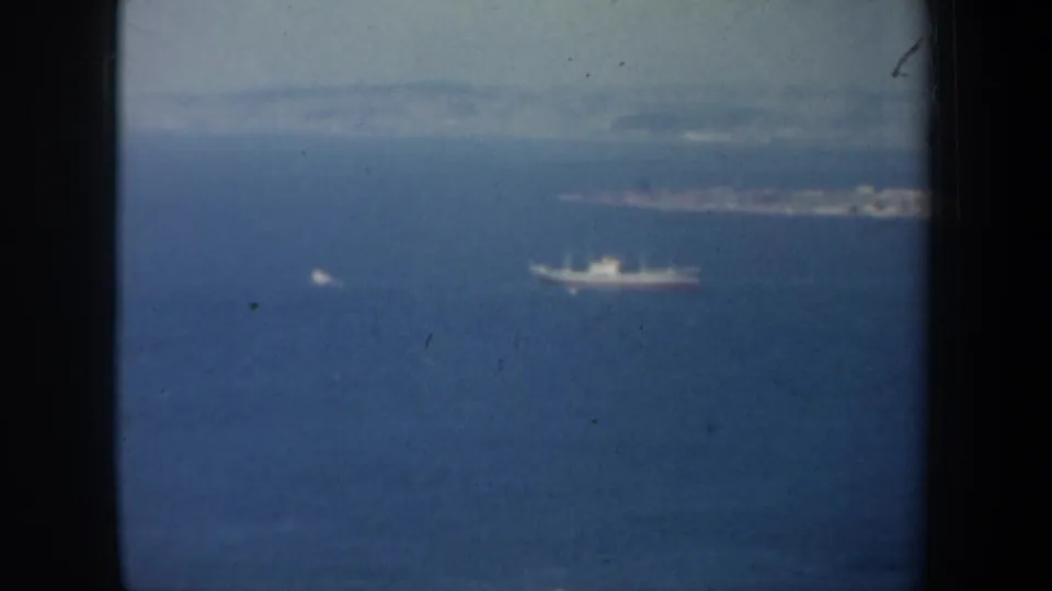 1957 San Francisco Bay view looking past a white ship toward a low shoreline and distant hills in soft haze.