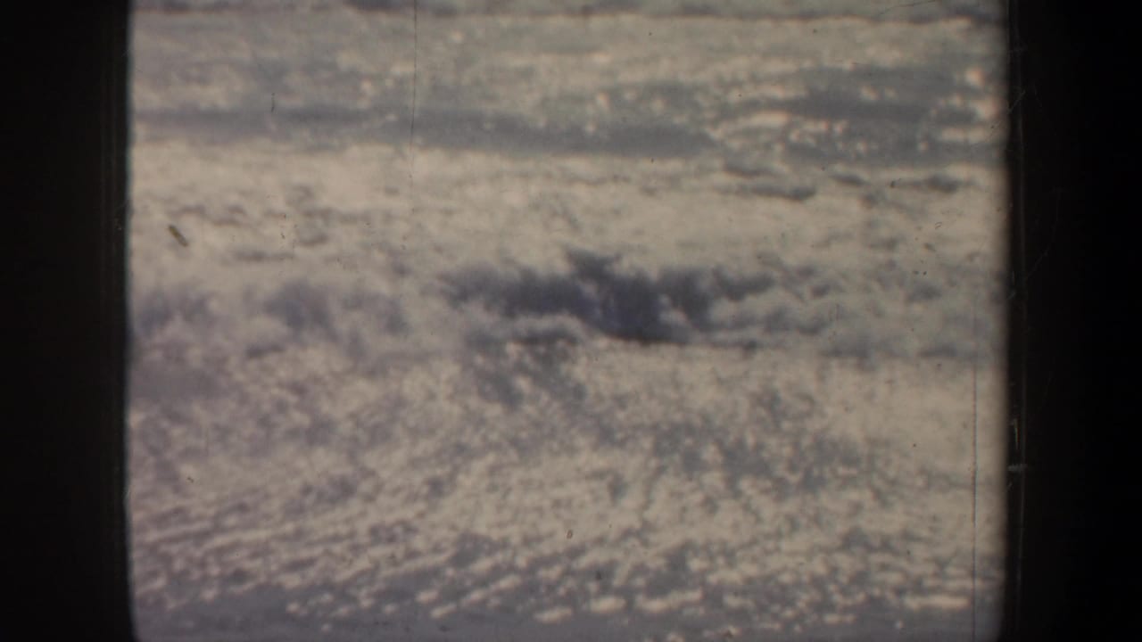 Soft 8mm view of churning beach surf in San Francisco, partially blocked by a dark pier support.