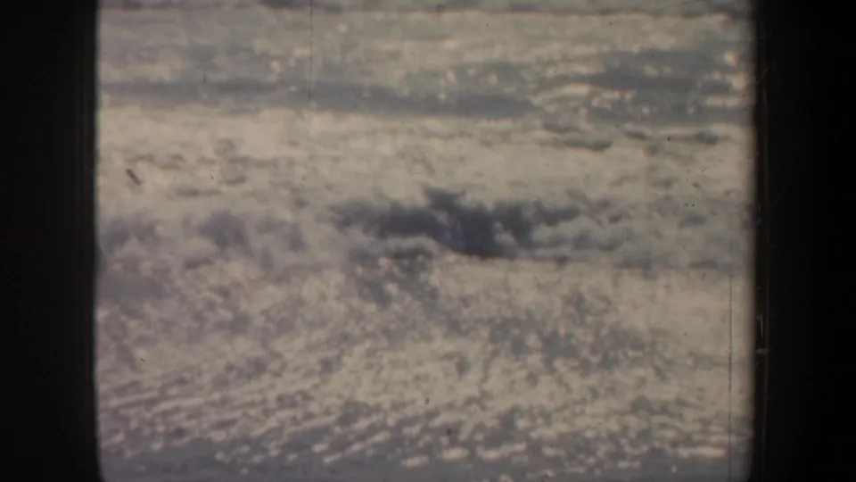 Soft 8mm view of churning beach surf in San Francisco, partially blocked by a dark pier support.