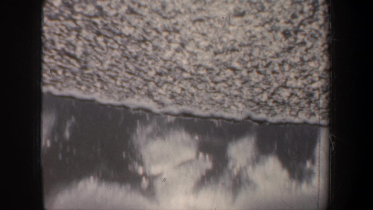 Foamy shoreline or waves partially obscured by a dark vertical frame edge.