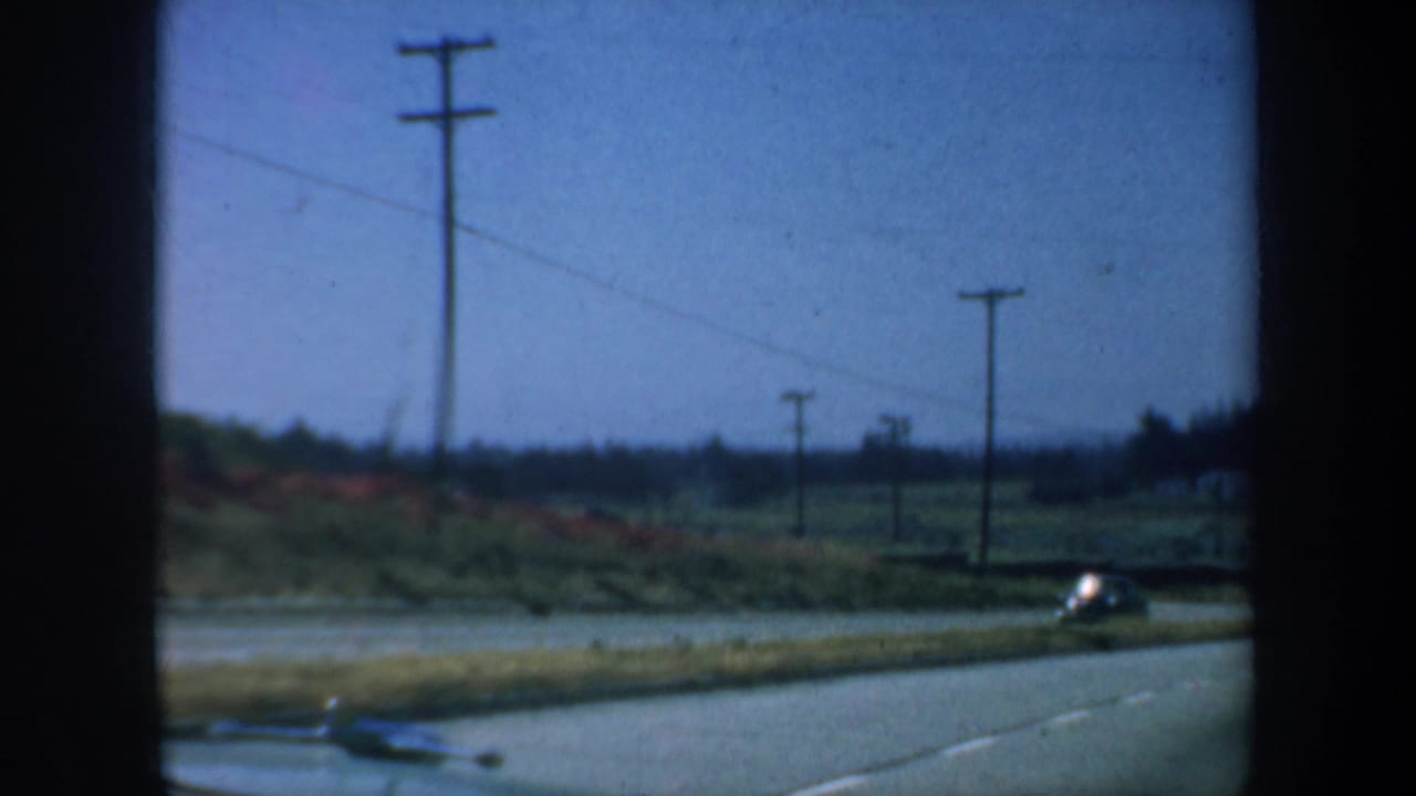 Roadside view with utility poles and a car approaching near the right edge.