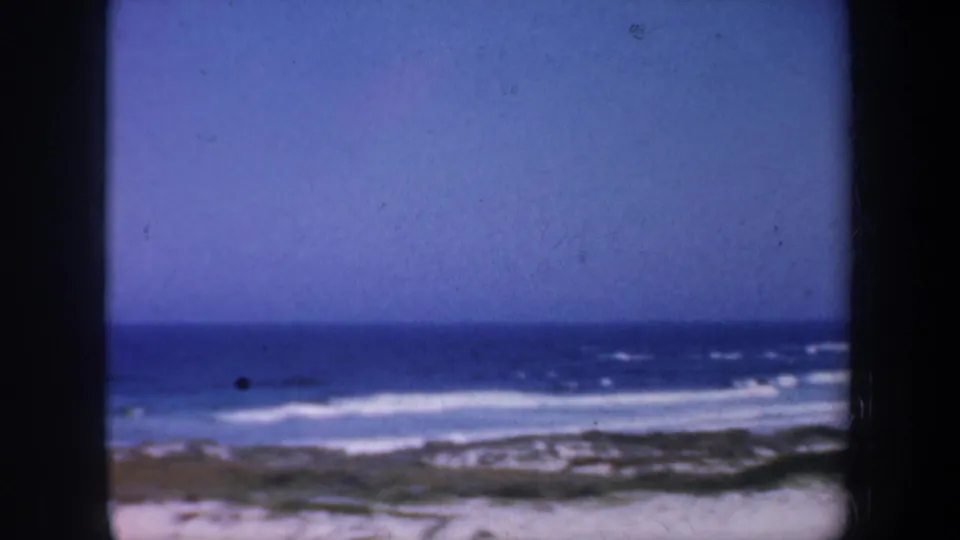 Coastal view from the 1957 San Francisco-area home movie, showing ocean waves breaking near a rocky shore.