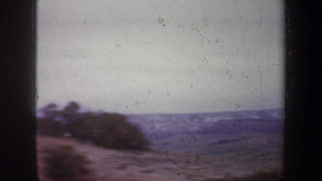 Soft, hazy view of a sloped hillside and distant terrain beneath a pale sky.