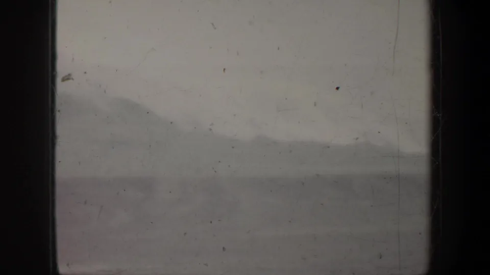 1957 Oregon 8mm frame showing a soft, foggy mountain ridge with dark film gate edges and visible dust marks.