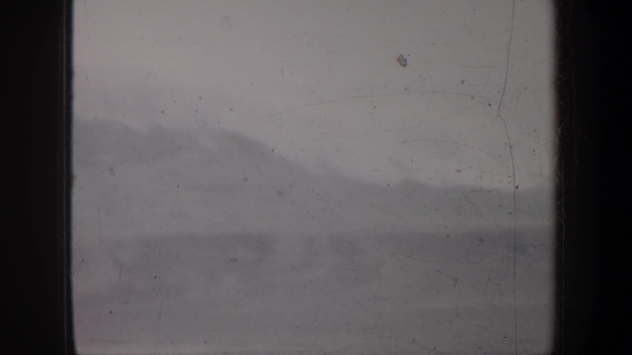 Soft mountain silhouette with pale snow and heavy dark border at center.