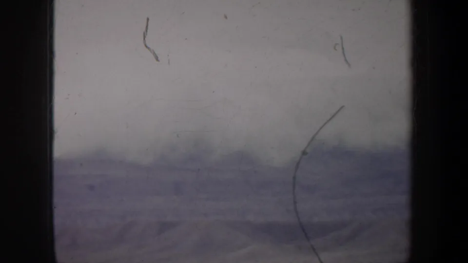 1957 Oregon 8mm view of a muted snow-covered landscape with soft focus, dust, scratches, and uneven exposure.