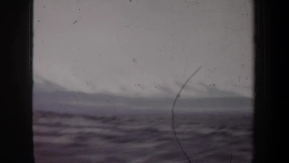 Soft 8mm view of open water, a hazy distant line, and dark vertical frame edges during the boat sequence.