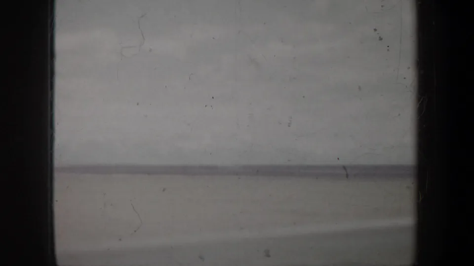 Very soft 8mm landscape or waterline view, mostly gray, with visible dust, scratches, and dark film borders.