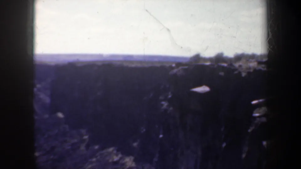 1957 Oregon 8mm frame showing a dim, wide canyon view with rocky cliffs and a pale horizon.