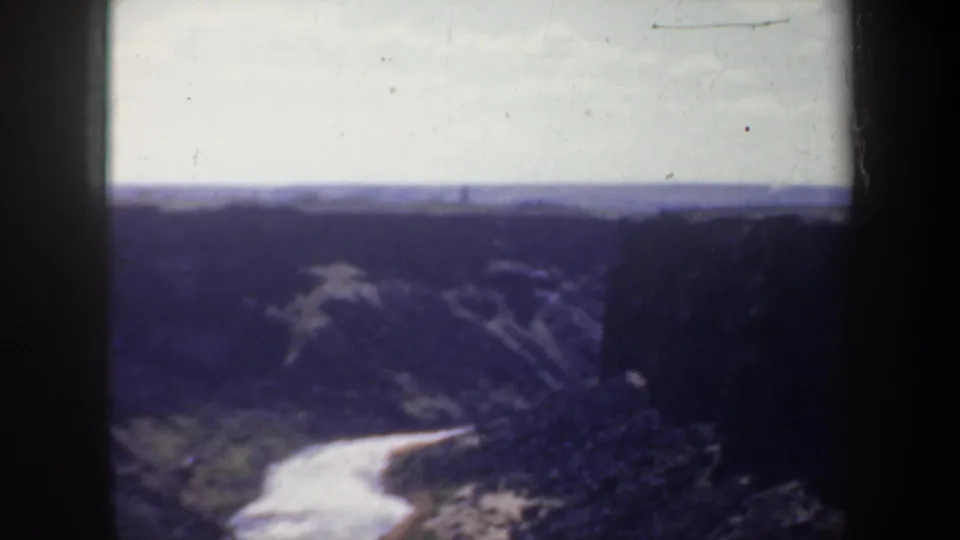 Vintage 8mm Oregon landscape frame showing a bright river bend below shadowed canyon walls.