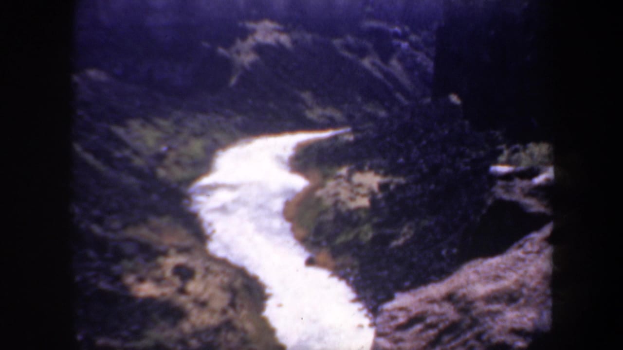 Winding pale watercourse bordered by rocky canyon walls and brush.