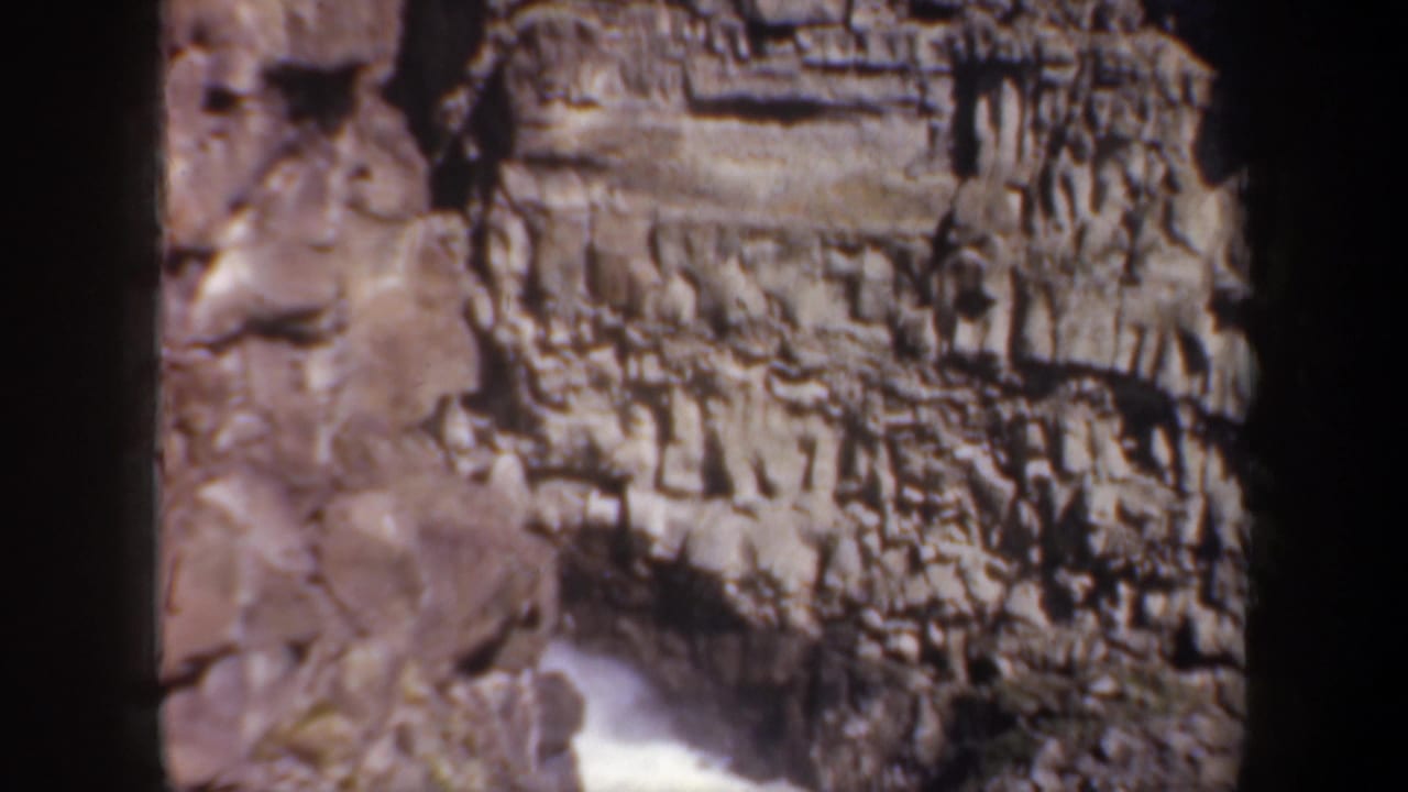 Rock canyon wall with white water beginning to appear below.
