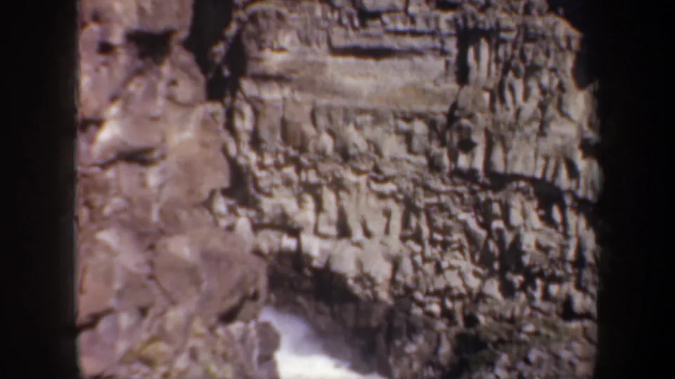 1957 Oregon home-movie frame looking across layered canyon rock as rushing white water appears at the lower edge.