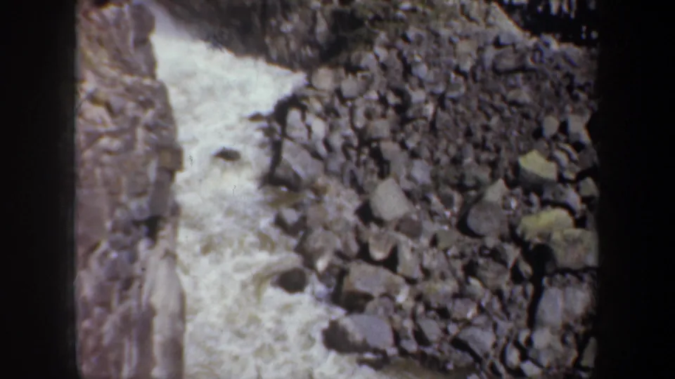 1957 Oregon home-movie frame looking down at a waterfall channel with boulders and steep rock walls.