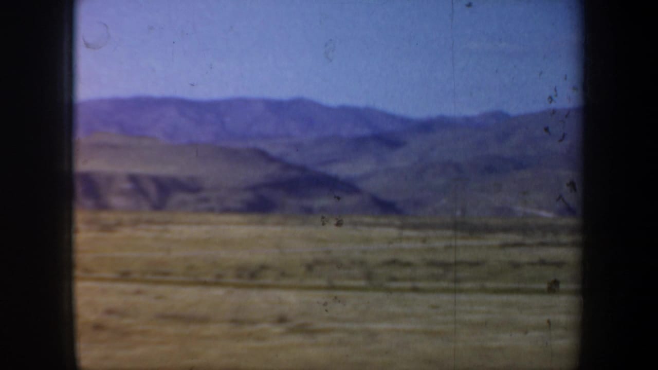 Purple mountain ridge and scrubby plain viewed through a window opening.