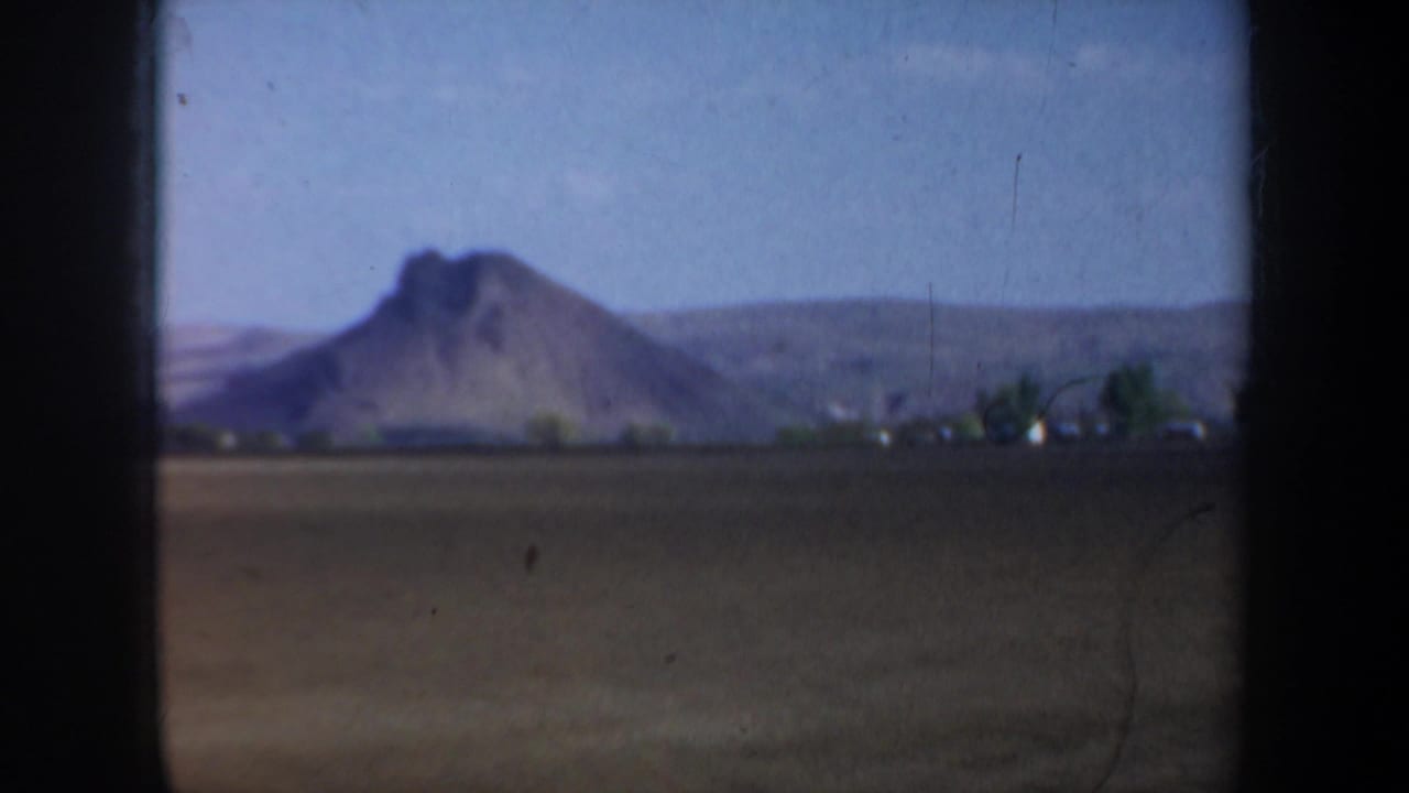 Open farmland with a prominent distant hill or mountain beyond the field.