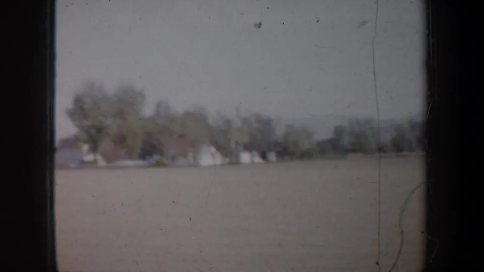 Moving 8mm view near Portland in 1957, with open land in the foreground and houses partly hidden by trees.