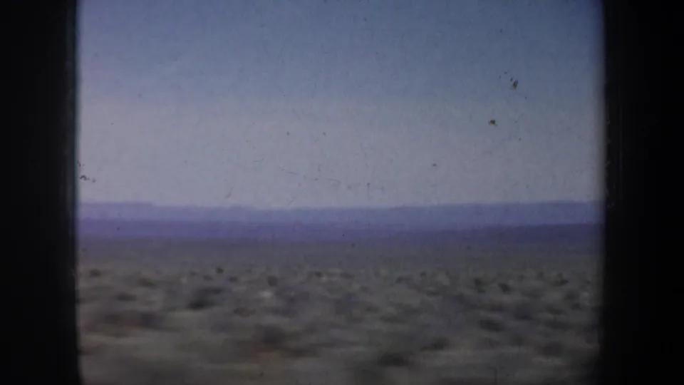 The final 1957 frame shows flat scrub terrain, a far ridge, and visible film wear under a pale blue sky.