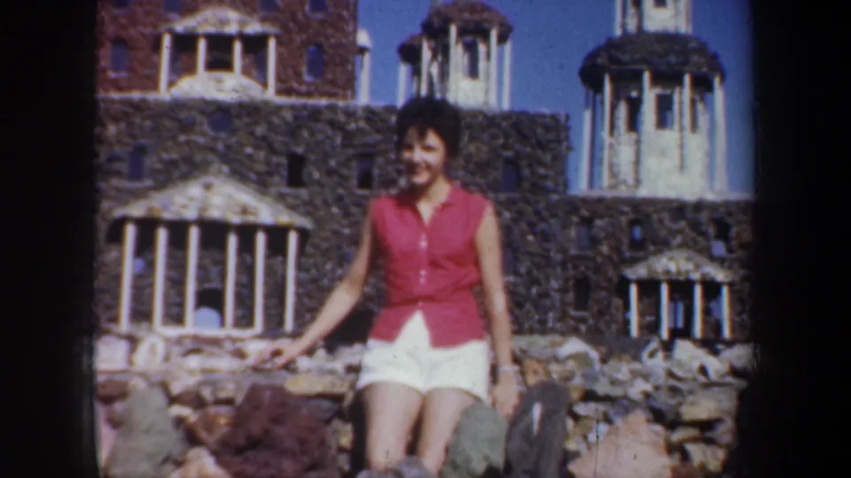 Woman remains posed at the miniature architecture site in the supplied 1957 Portland, Oregon home-movie footage.