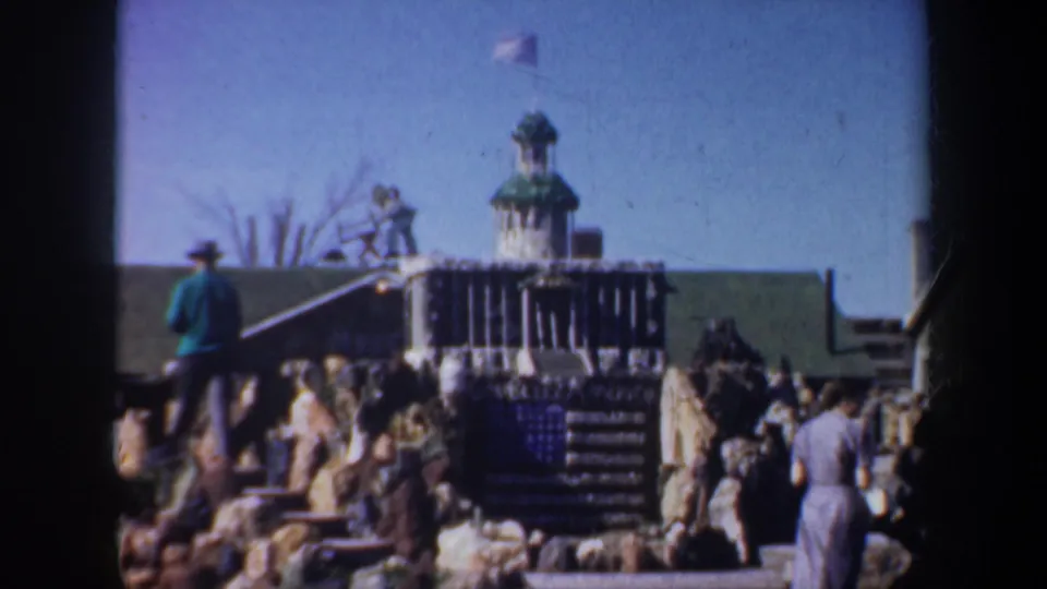 Visitors explore the rocky landmark area, with steps, stonework, and a small tower visible in the 1957 Portland home-movie scene.