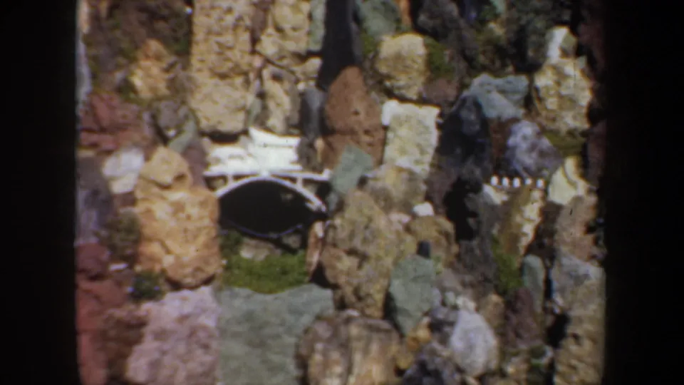 1957 Portland 8mm frame showing a small arched bridge or opening built into a rocky garden miniature.
