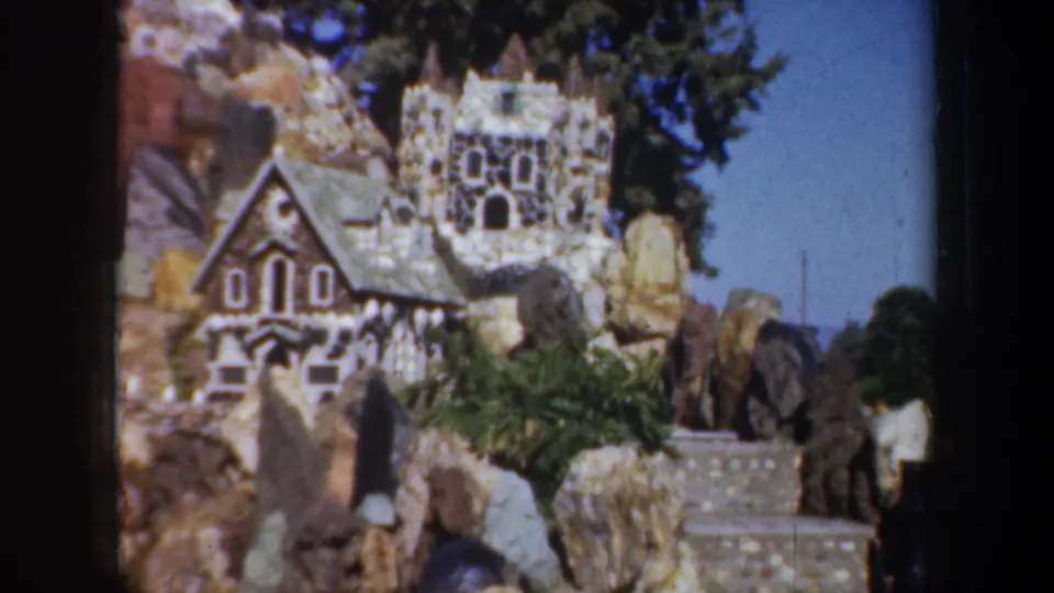 1957 Portland 8mm frame showing a castle-like miniature and small house form in a rock garden display.