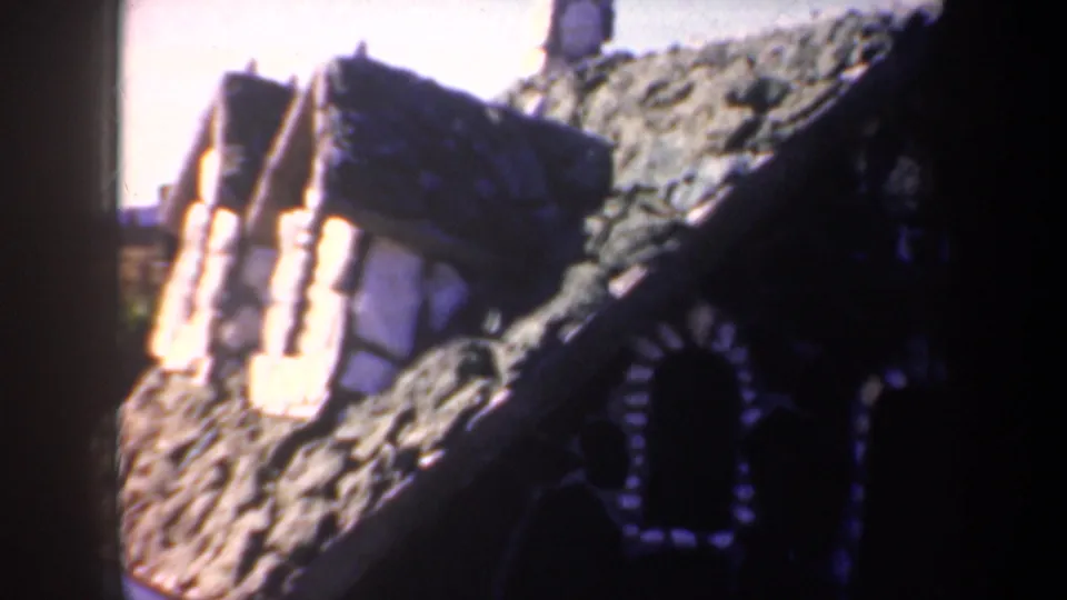 1957 Portland 8mm frame showing a textured rooflike surface, bright exposure flare, and dark arched decorative detail below.