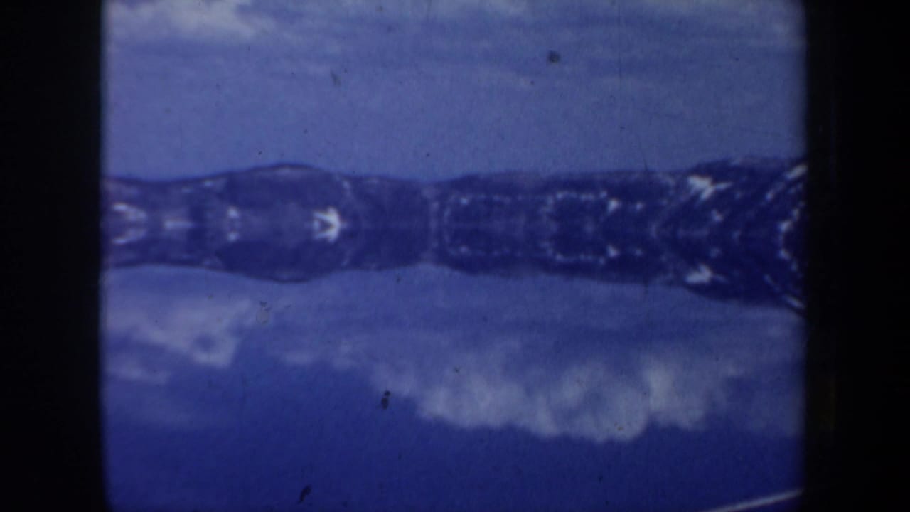 Blue-toned water or ice with a dark distant ridgeline and snowy patches.