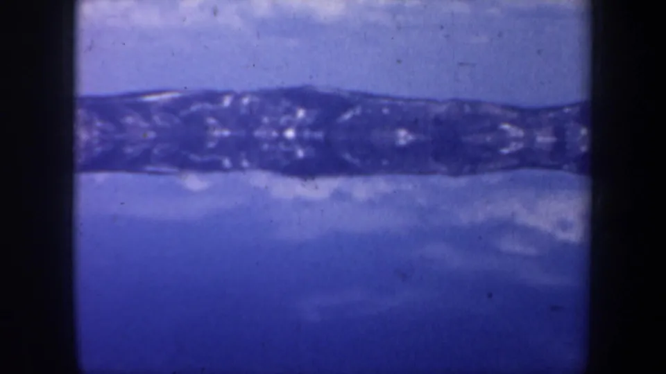 Final 8mm frame of the Oregon winter landscape pan, with a dark ridgeline and blue water or ice under soft, faded color.