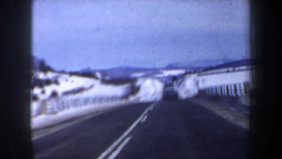 The final frame shifts to a more open snowy New Hampshire roadside, with pavement, roadside fencing, hills, and winter sky visible.