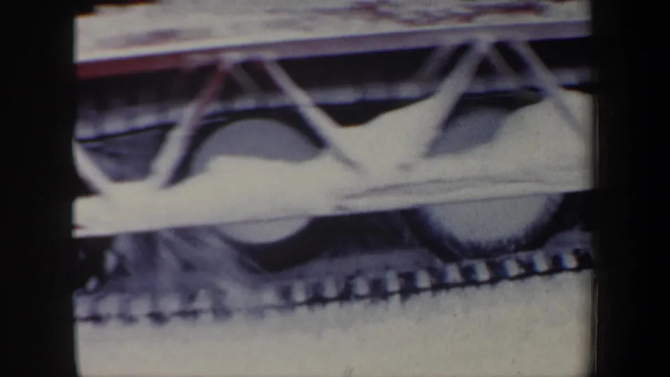 Detail frame from the 1962 New Hampshire clip showing the snow vehicle's tracked mechanism and snow-covered front assembly.