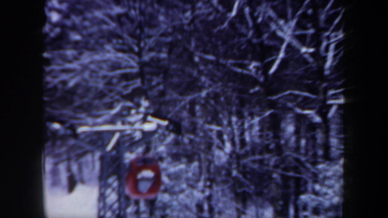 Red ski lift car on a cable among snow-covered trees.