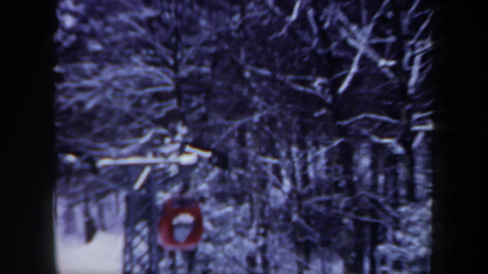 Red lift car traveling through a snowy New Hampshire forest in a 1962 8mm home-movie frame.