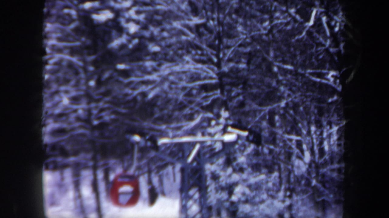 1962 New Hampshire 8mm frame showing a red ski-lift gondola moving through snow-covered forest.