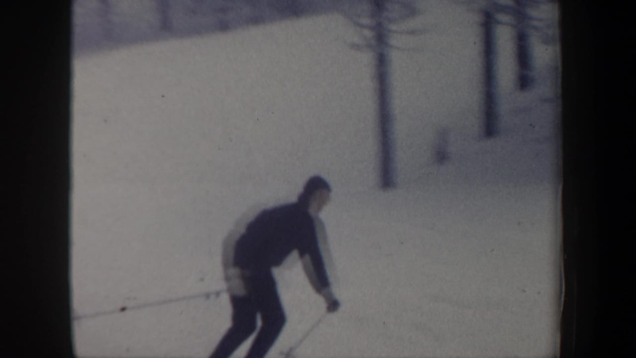 Skier leans forward while using poles on a bright snowy run.