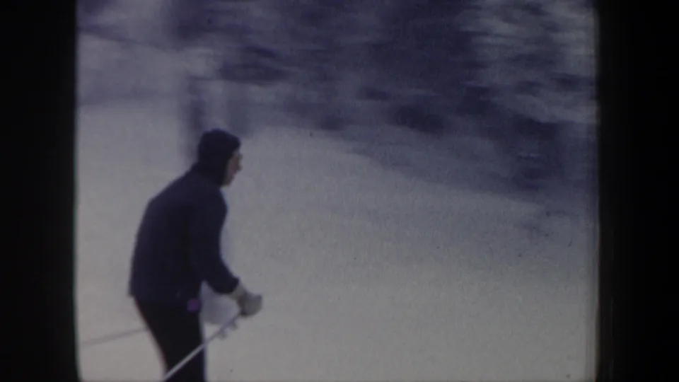 Side view of the adult skier in dark winter clothing during the snowy New Hampshire skiing sequence.