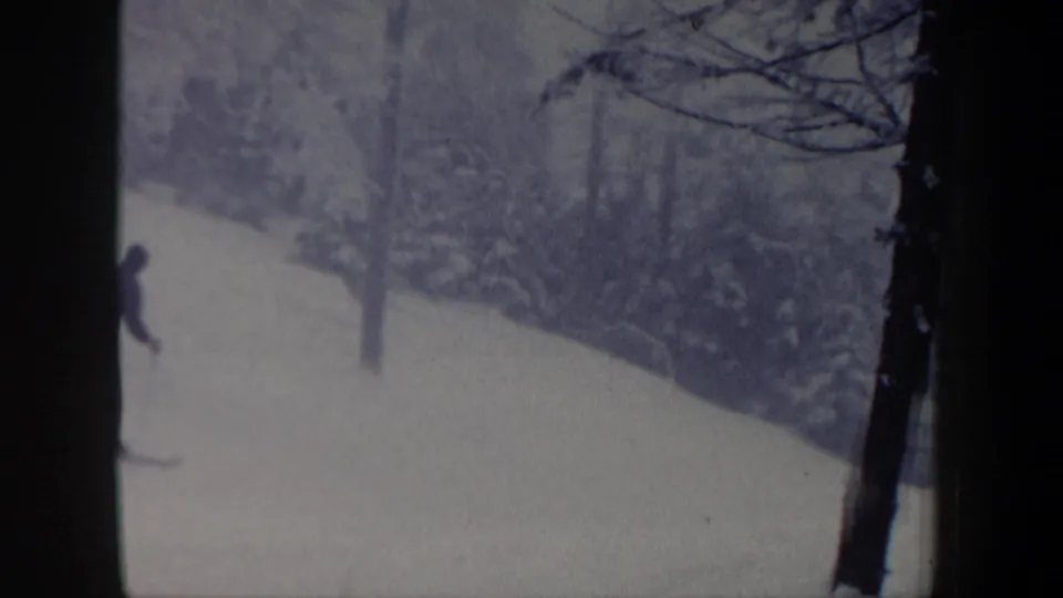 1962 New Hampshire 8mm frame with a skier partly visible near the left edge of a snow-covered forest slope.