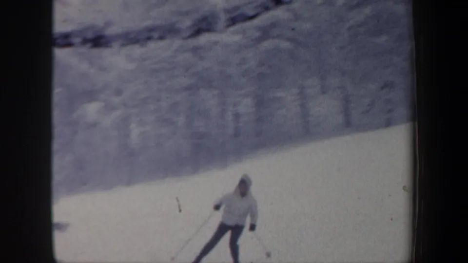 1962 New Hampshire 8mm frame showing a skier in a light jacket turning across a bright snow-covered slope.