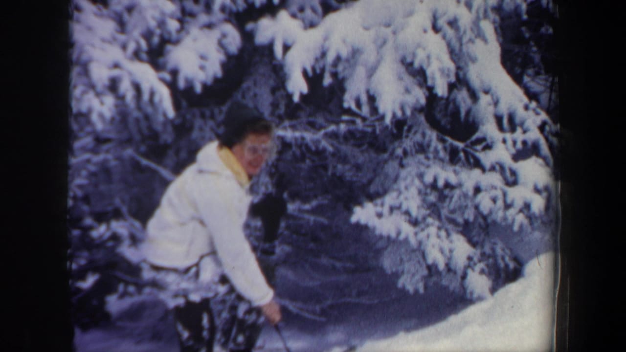 1962 New Hampshire 8mm frame with the skier looking toward the camera while crouched on a snowy forest slope.